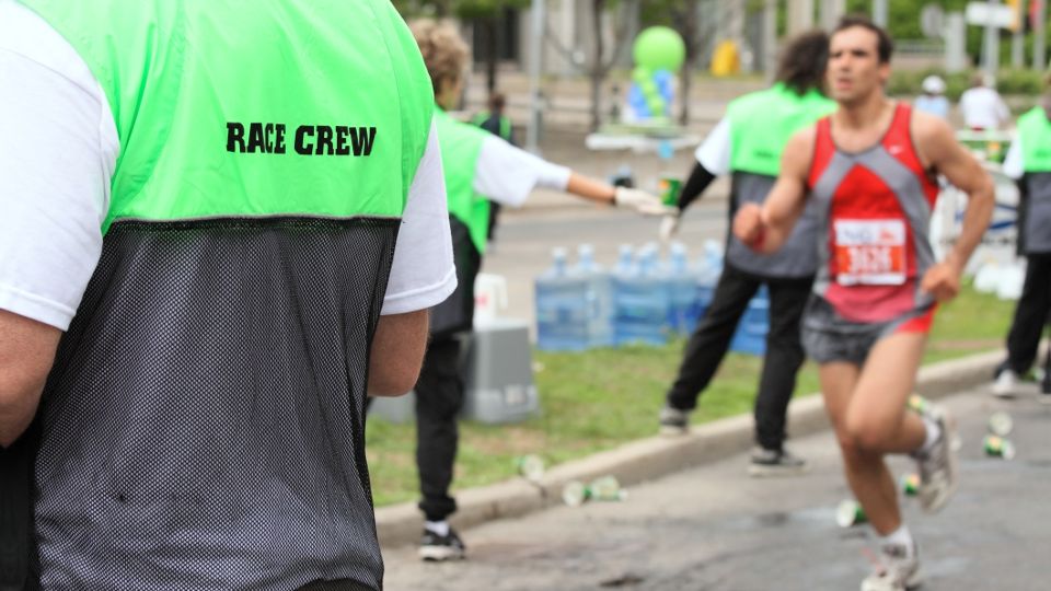 Race volunteer handing out water at a running event